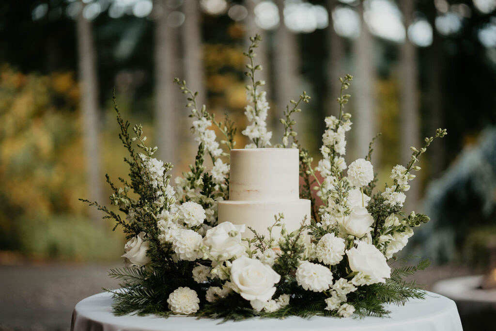 A white wedding cake surround by white flowers. 