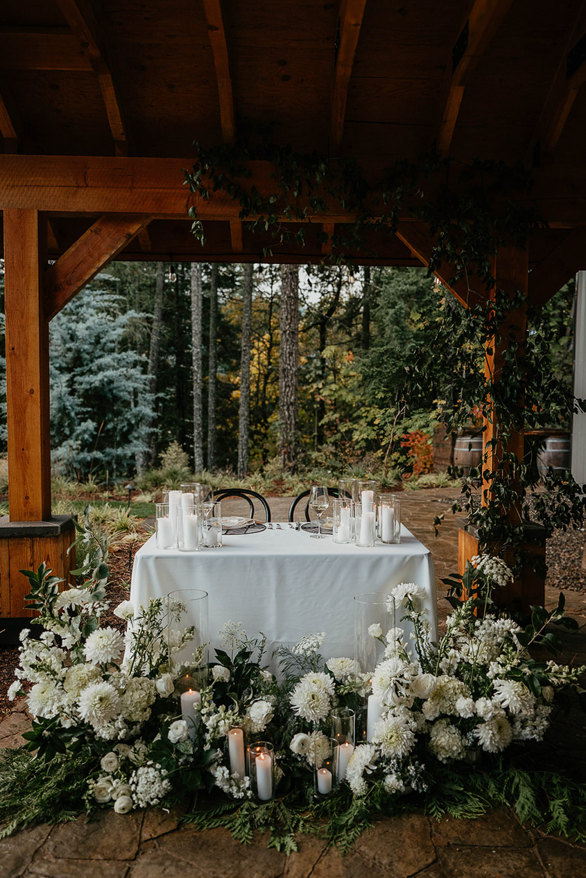 The sweetheart table, complete with candles and surrounded by flowers and greenery. 