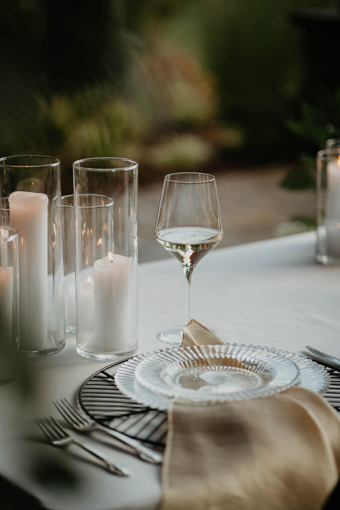 Table details including clear china, white candles, and wine glasses. 
