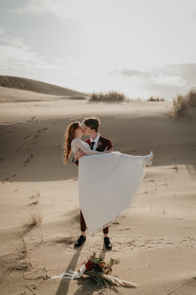 Bride and groom kiss during their Oregon elopement on the sand dunes