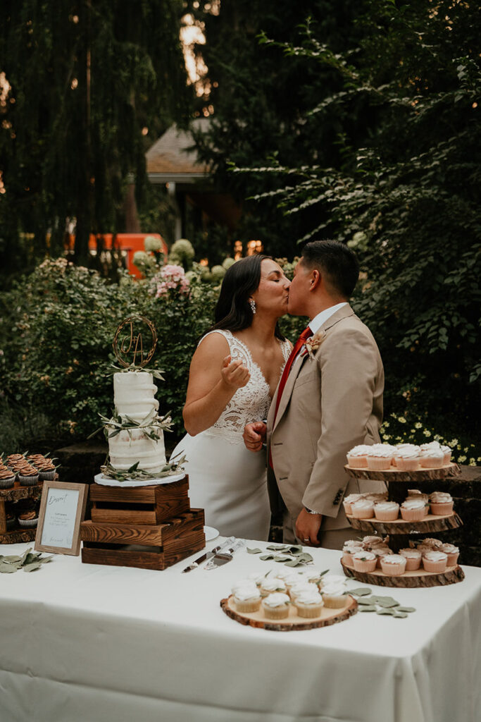 The newlyweds kissing by the wedding cake. 