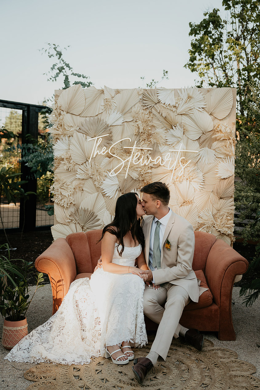 the newlyweds kissing under a neon sign of their last name. 