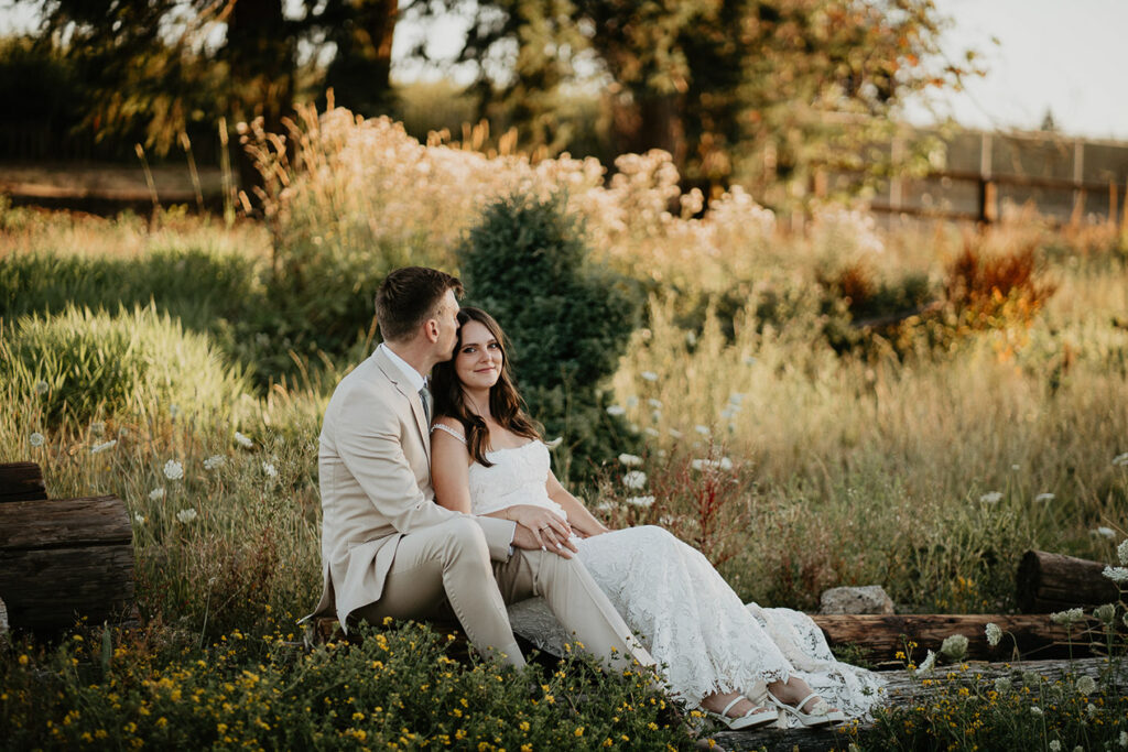 the newlyweds sitting in a field at golden hour. 