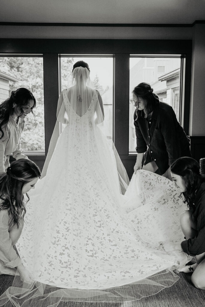the bridesmaids helping the bride with her dress. 