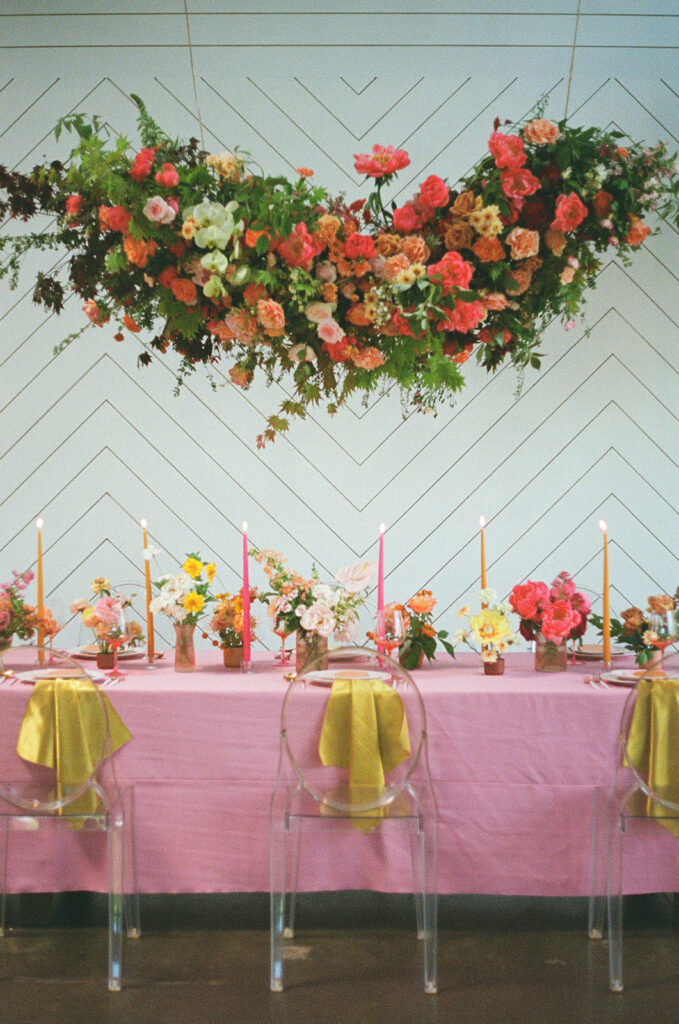 Hot pink wedding reception table with bright floral installations and candlestick decorations