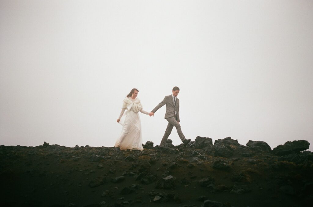Bride and groom hold hands while walking around a trail during their Iceland wedding