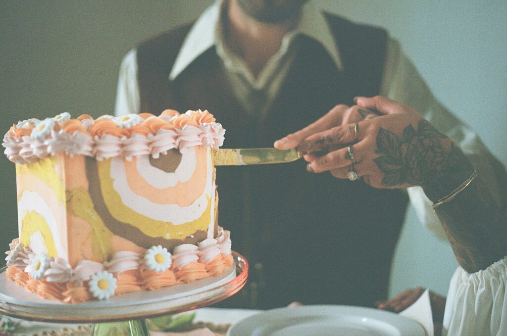 Groom cuts into 70s themed wedding cake 