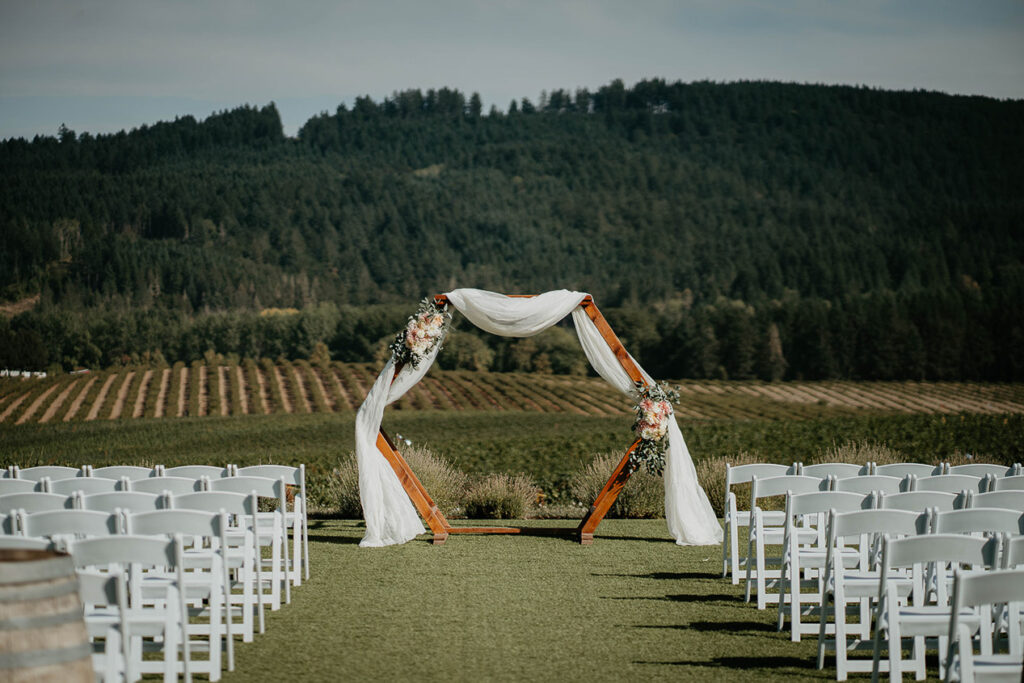 The wedding ceremony location, which is on a grassy lawn with farmland and trees in the background. 