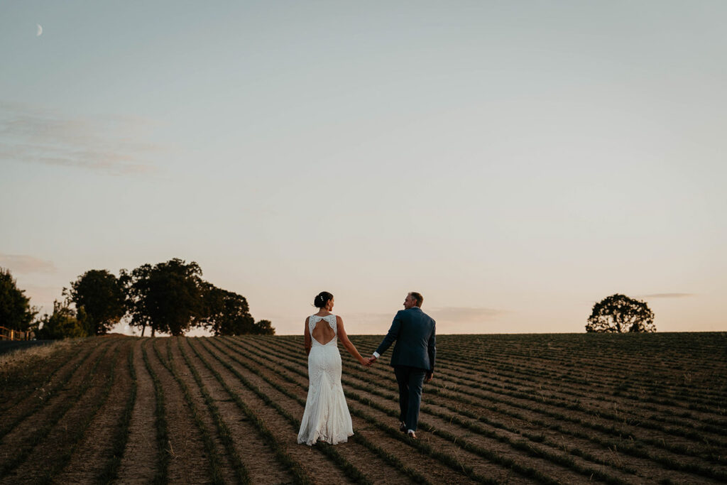 A couple walking on a field at Abbey Road Farm at sunset. 