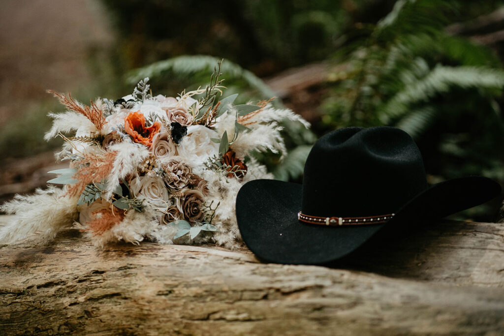 a cowboy hat and a bouquet of flowers sitting on a fallen tree trunk. 