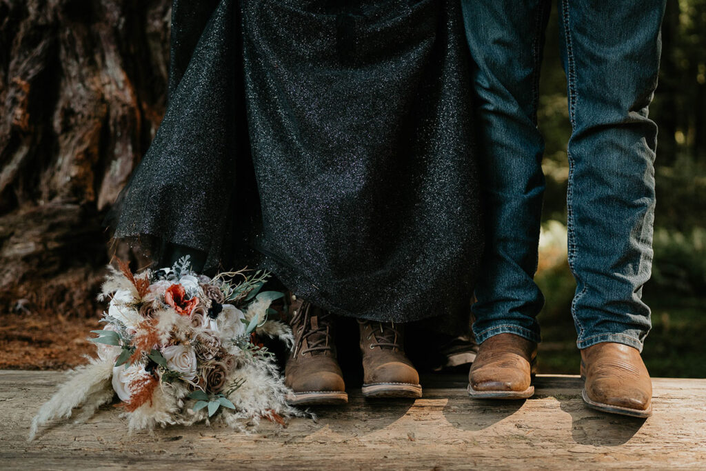 the newlyweds showing off their boots standing on a fallen tree trunk.