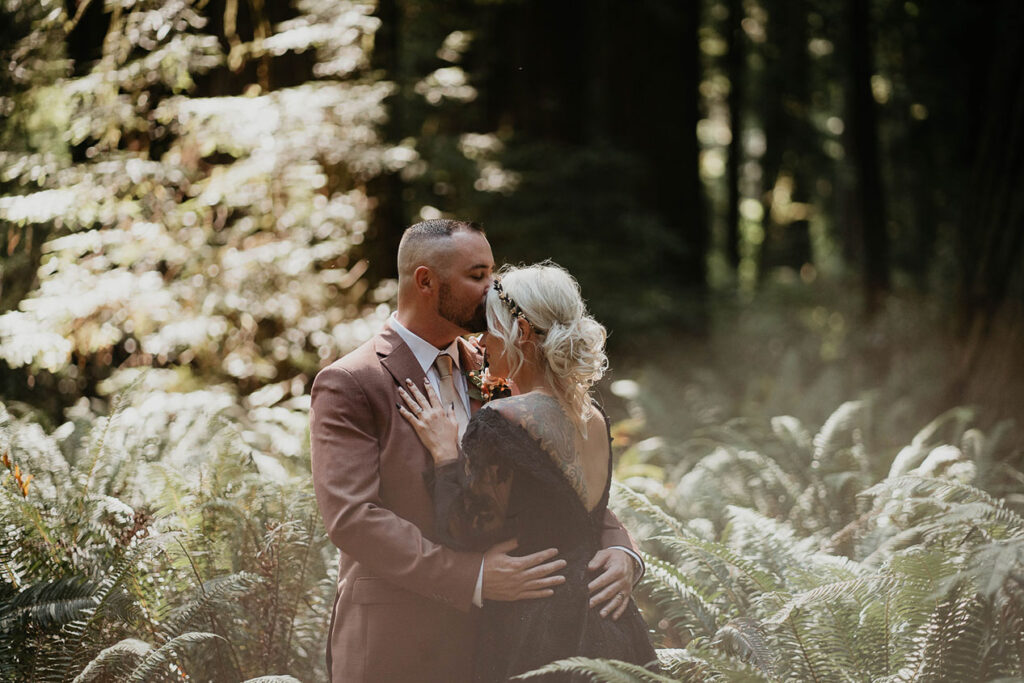 the husband kissing his wife with ferns in the background. 