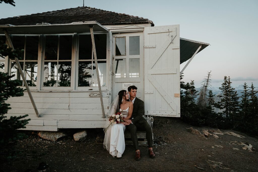 Bride and groom sit on the steps of a fire lookout during their Washington elopement