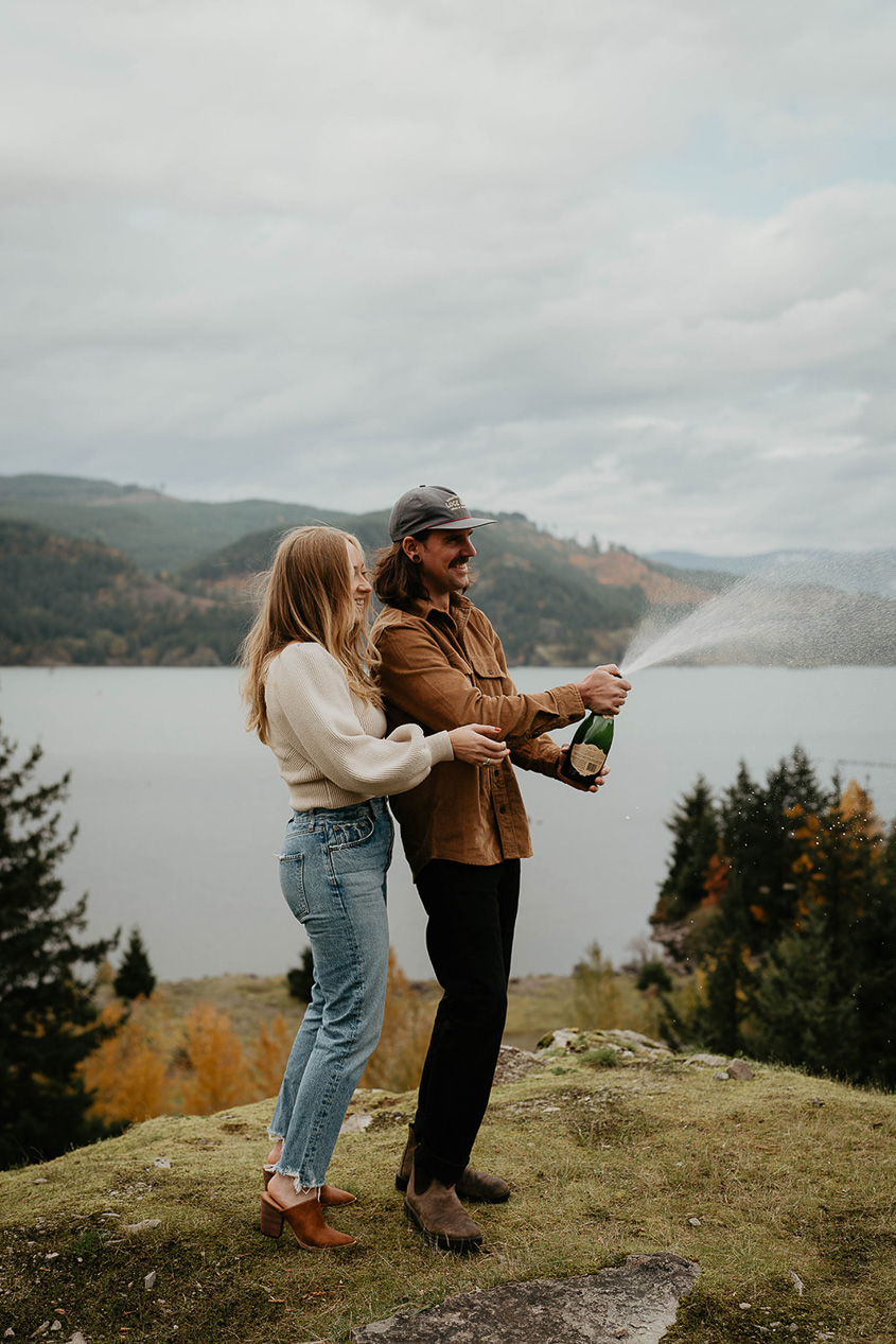a newly engaged couple spraying champagne in the Columbia River Gorge. 