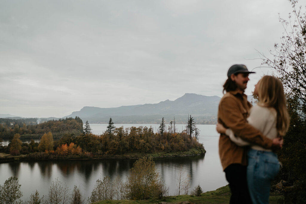 a newly engaged couple holding each other with the Columbia River Gorge in the background. 