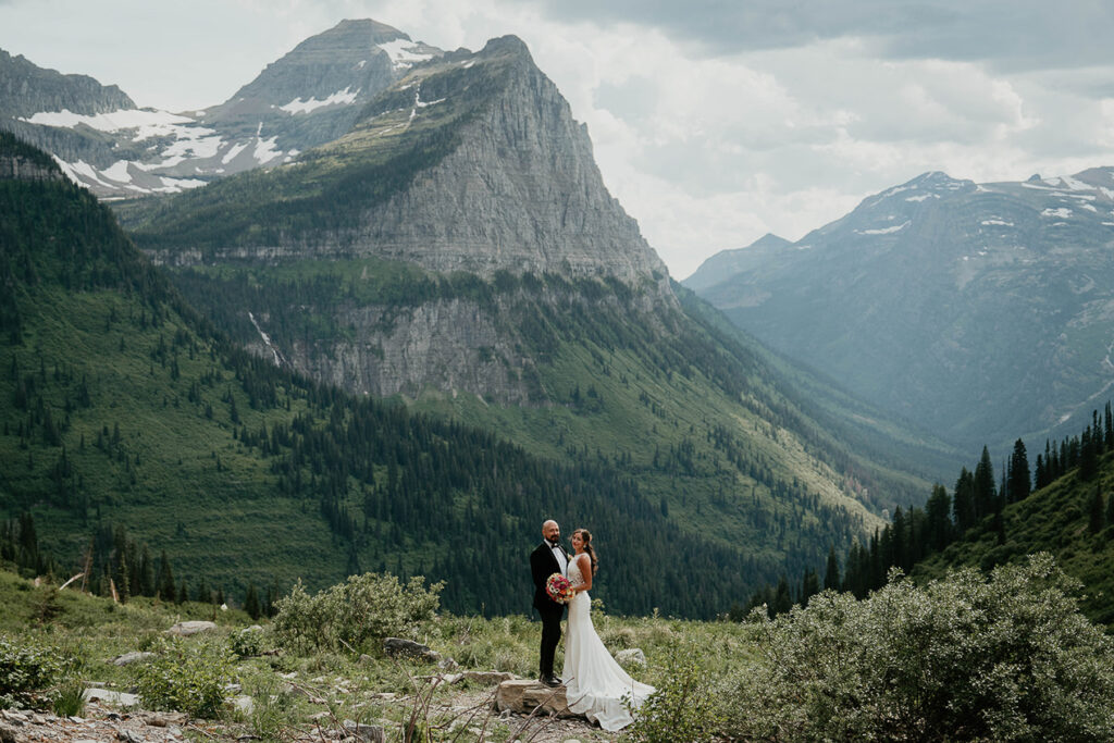 The newlyweds standing close with mountains in the background during their Glacier National Park Elopement. 
