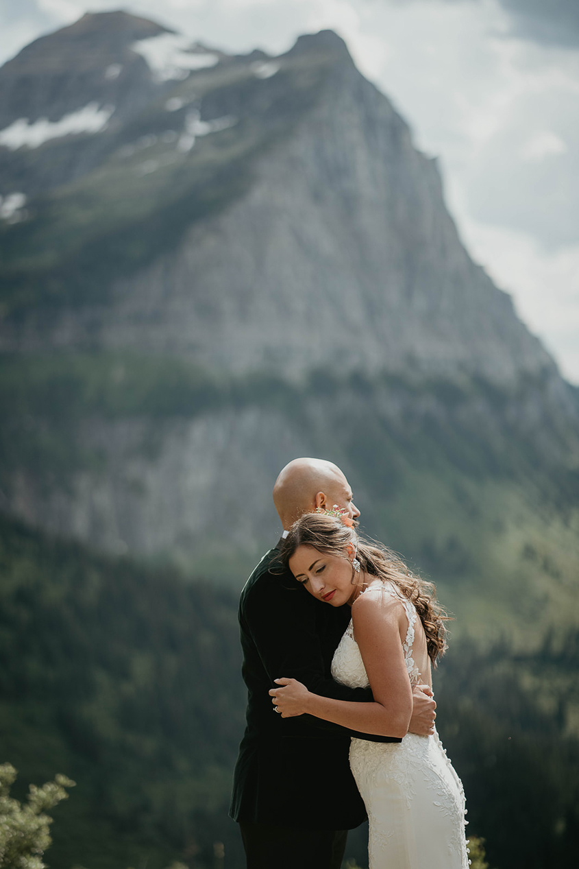 The newlyweds hugging with mountains and evergreens in the background. 