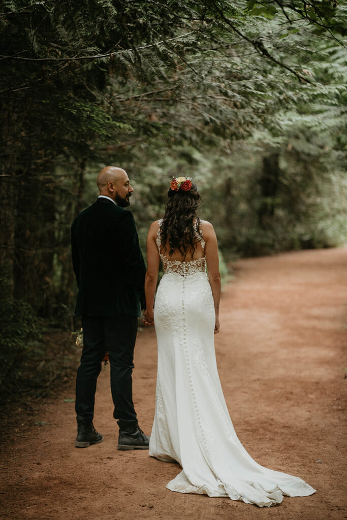 The couple holding hands and standing on a trail during their Glacier National Park elopement. 