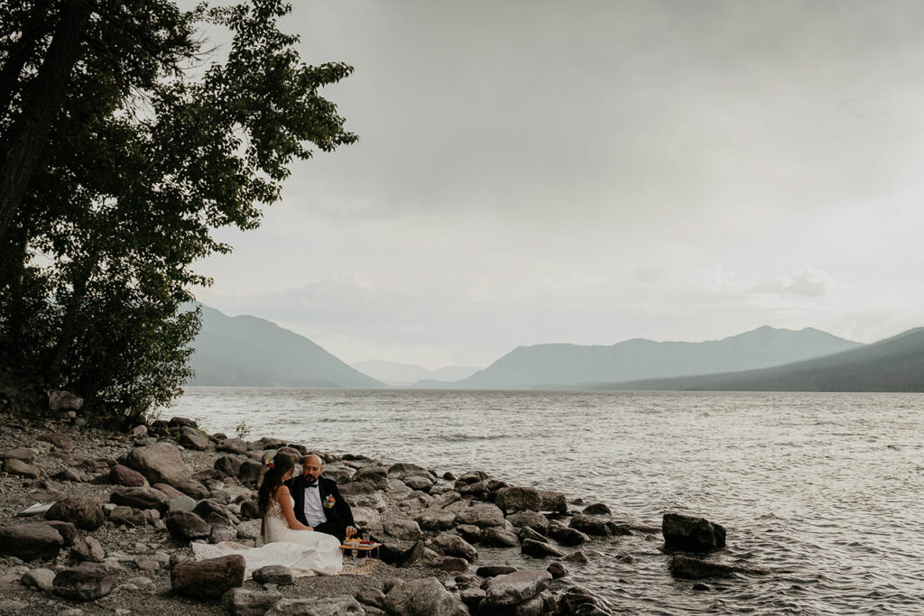 the couple having a picnic on the lakeshore during their Glacier National Park elopement. 