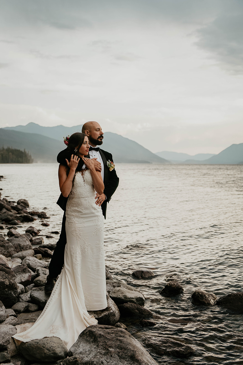 The newlyweds standing at the lakeshore in Glacier National Park.