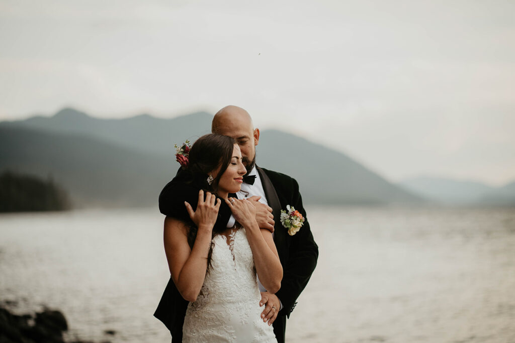 The couple embracing each other with a lake in the background. 