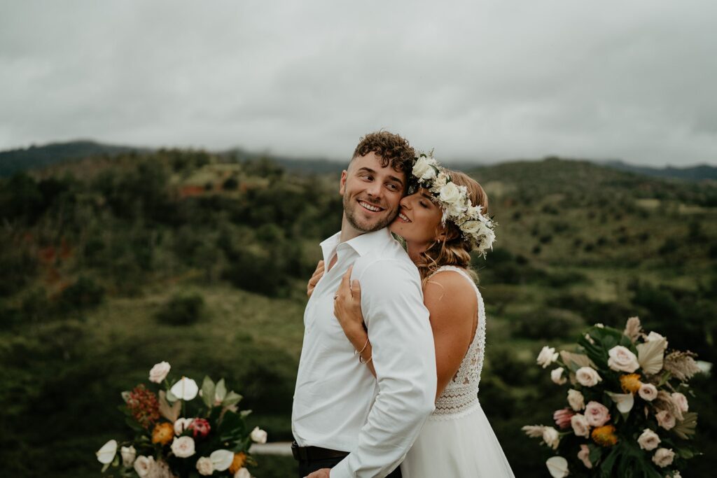 Bride hugs groom from behind while they elope in Hawaii