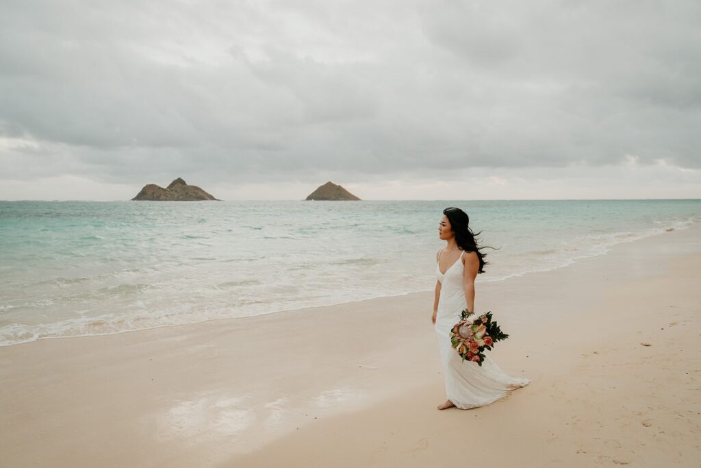 Bride walks along a white sand beach during her elopement in Kaua'i