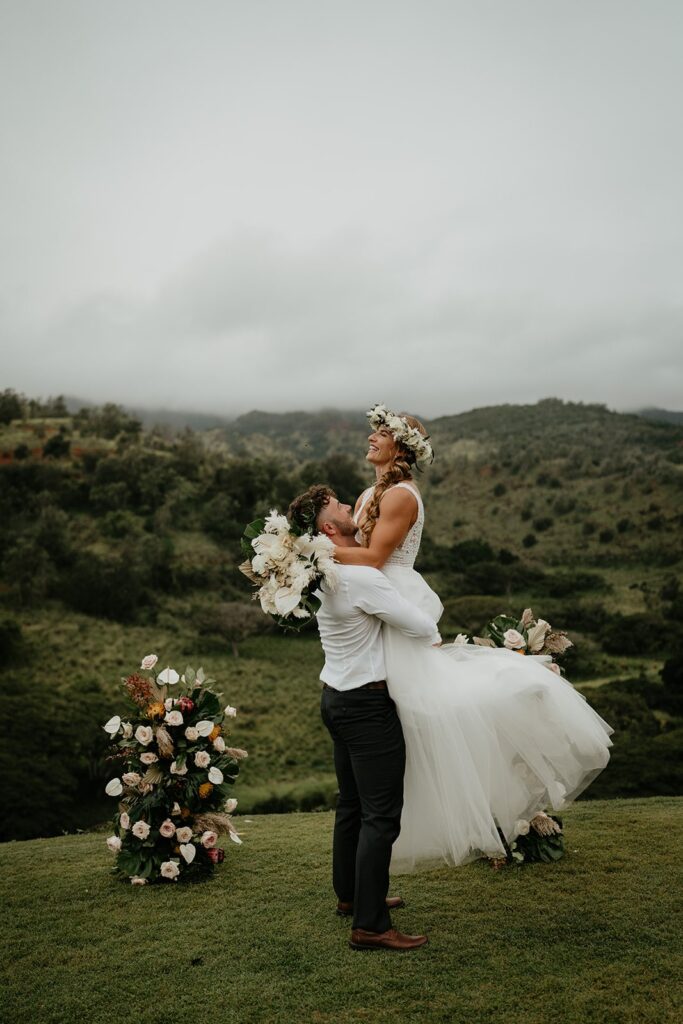 Groom lifts bride into their air during their elopement at Ka'ala Vista wedding venue.