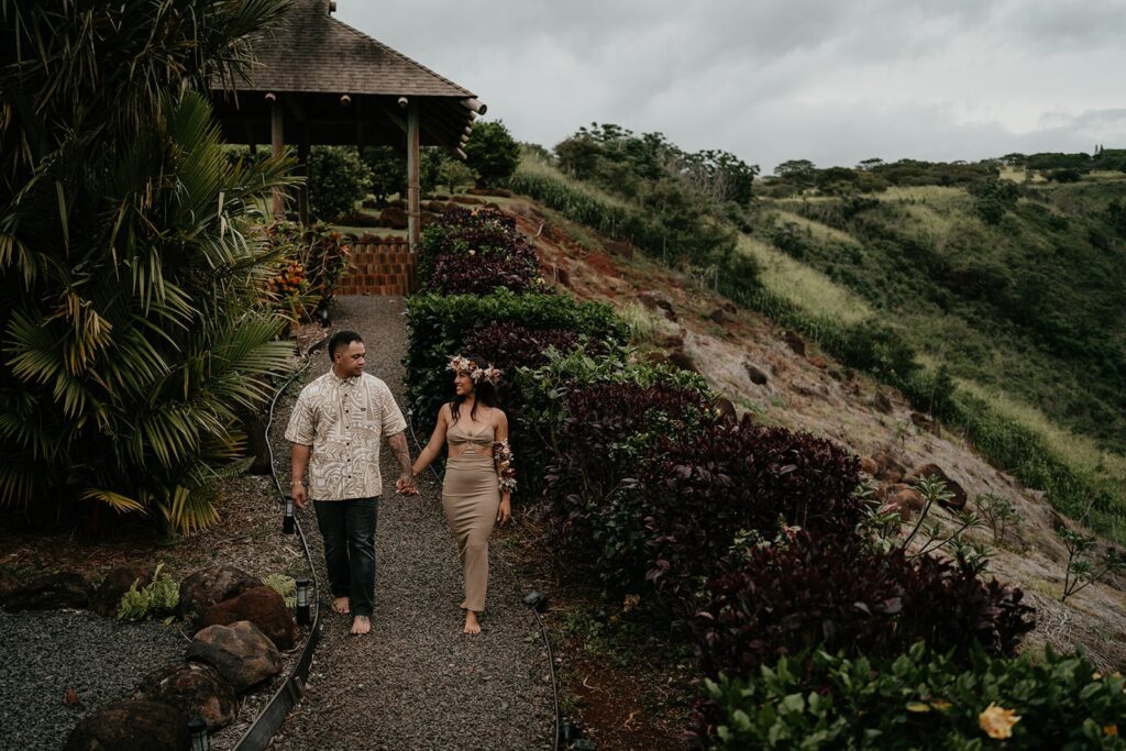 Bride and groom hold hands as they walk down a rainforest trail during their elopement in Hawaii