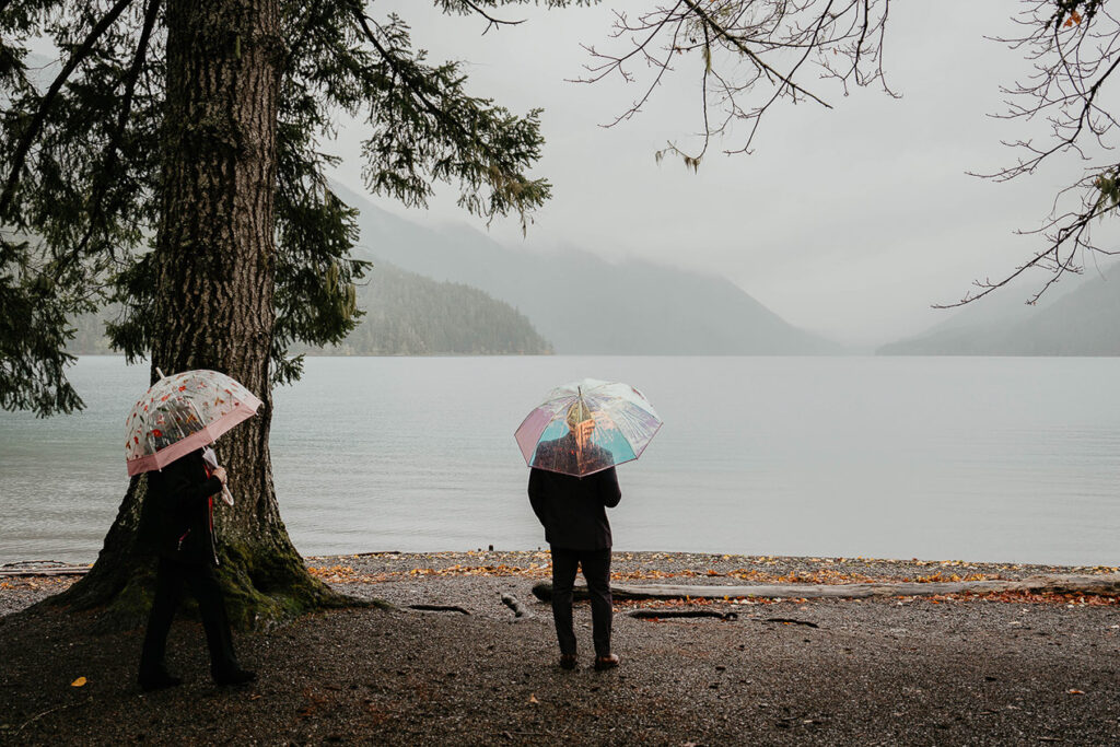 The bride and groom with umbrellas at Lake Crescent. 