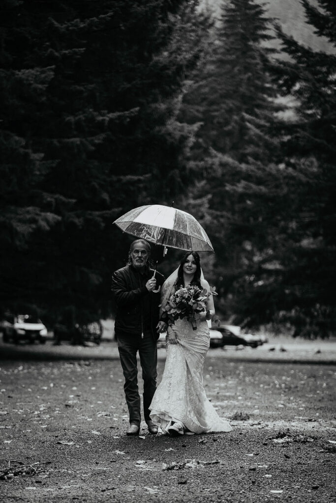 The bride and groom walking together with an umbrella. 