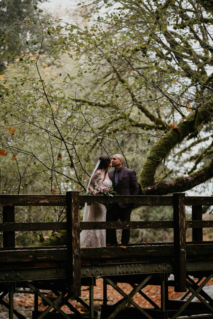 The bride and groom kissing on a bridge. 