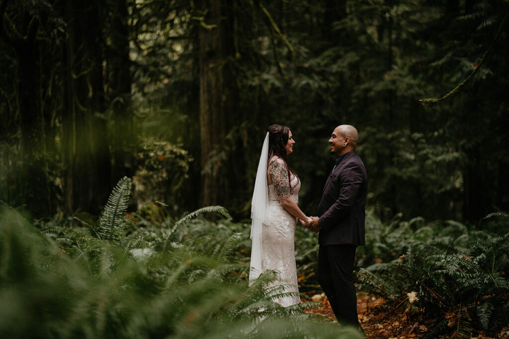 The bride and groom holding hands in the forest. 