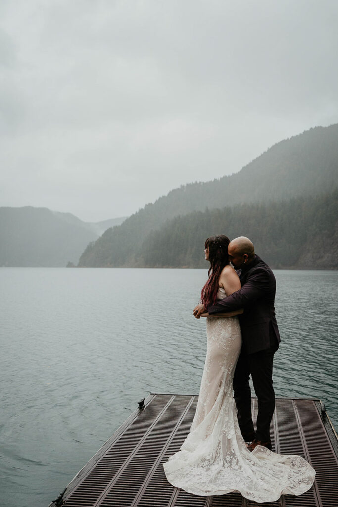 The newlyweds holding each other on a dock at Lake Crescent during their elopement. 