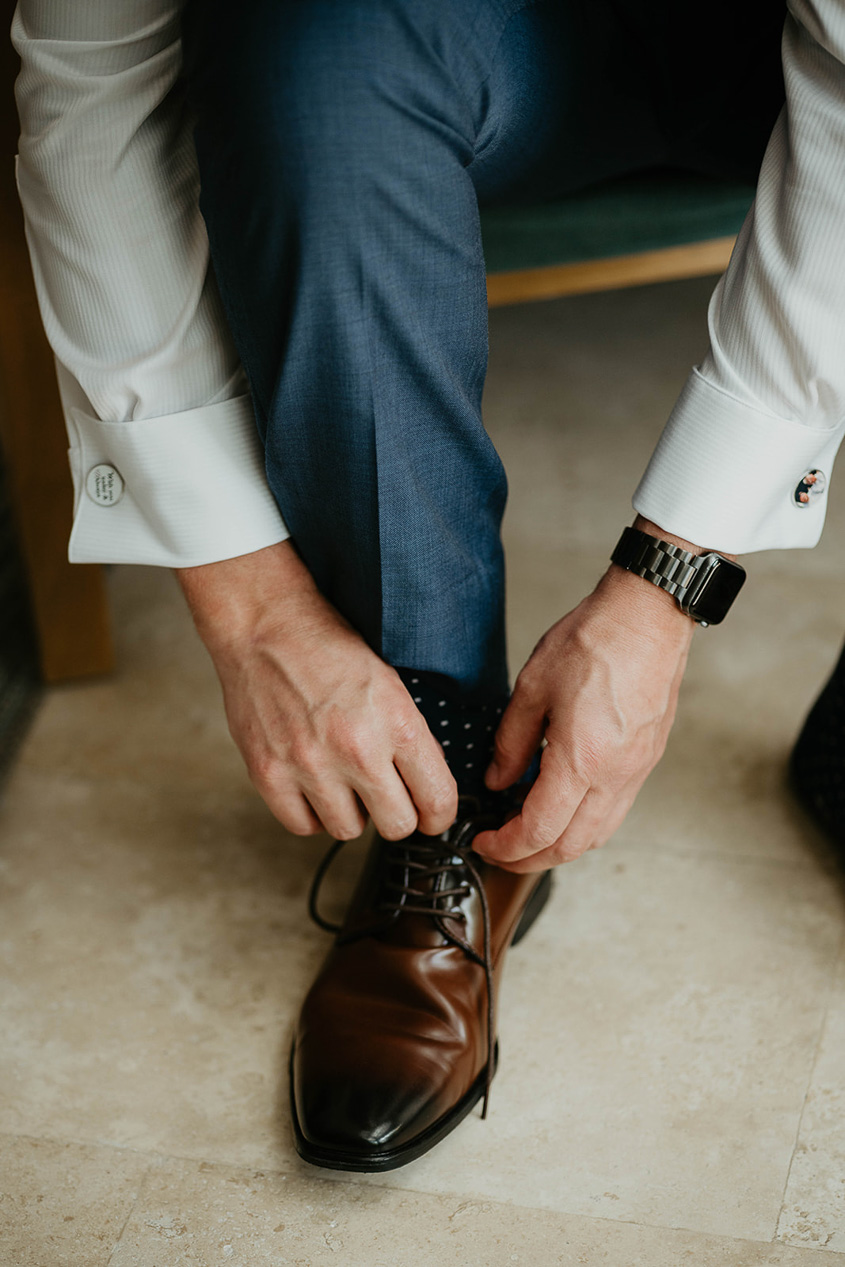 The groom tying his shoes. 