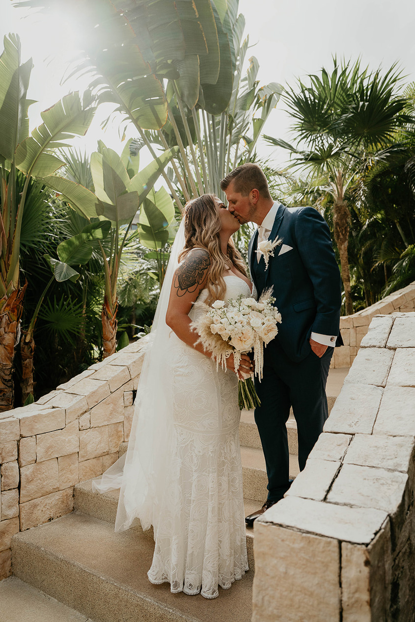 The bride and groom kissing on a set of stairs during their Mexico destination wedding. 
