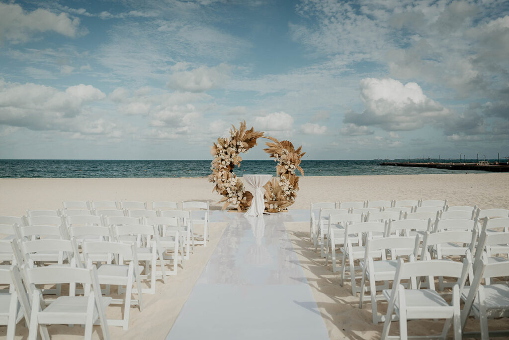 The Mexico destination wedding ceremony venue, with folding chairs and an altar on the beach, with the pacific ocean in the background. 