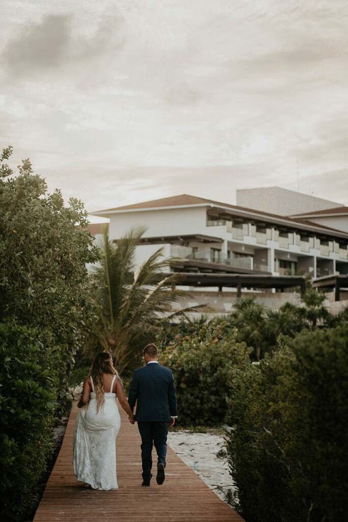 The bride and groom walking on a boardwalk during their Mexico destination wedding. 