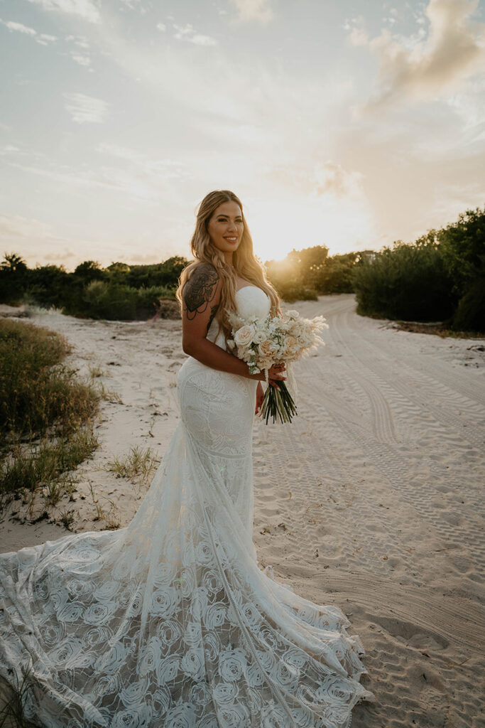 The bride posing on the sand at sunset during their Mexico destination wedding.