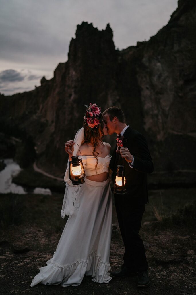 Bride and groom kiss while holding lanterns during their blue hour elopement at Smith Rock State Park