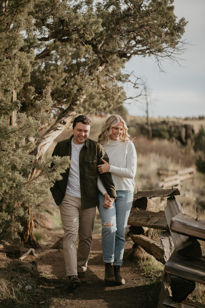 A couple holding hands walking toward the camera on a trail. 