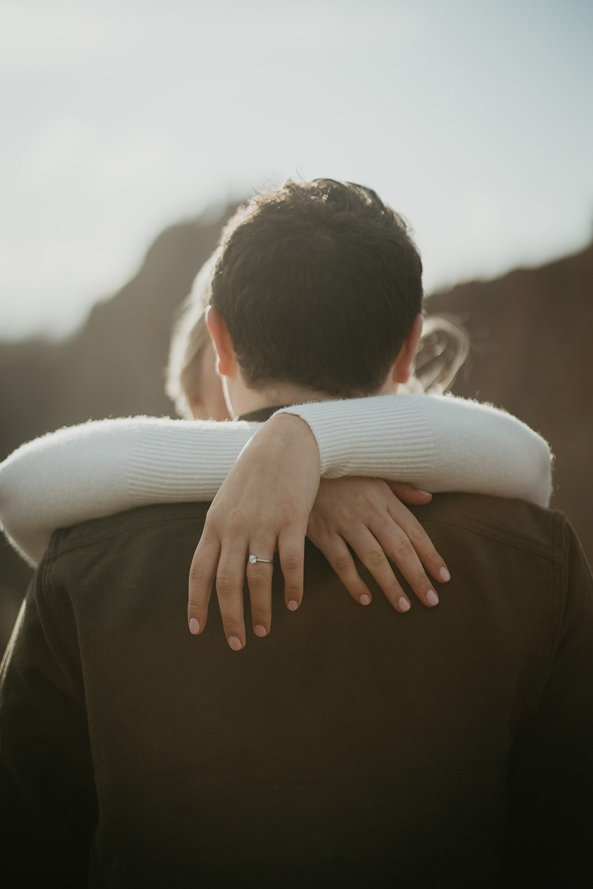 The couple hugging, highlighting the soon-to-be bride's engagement ring. 