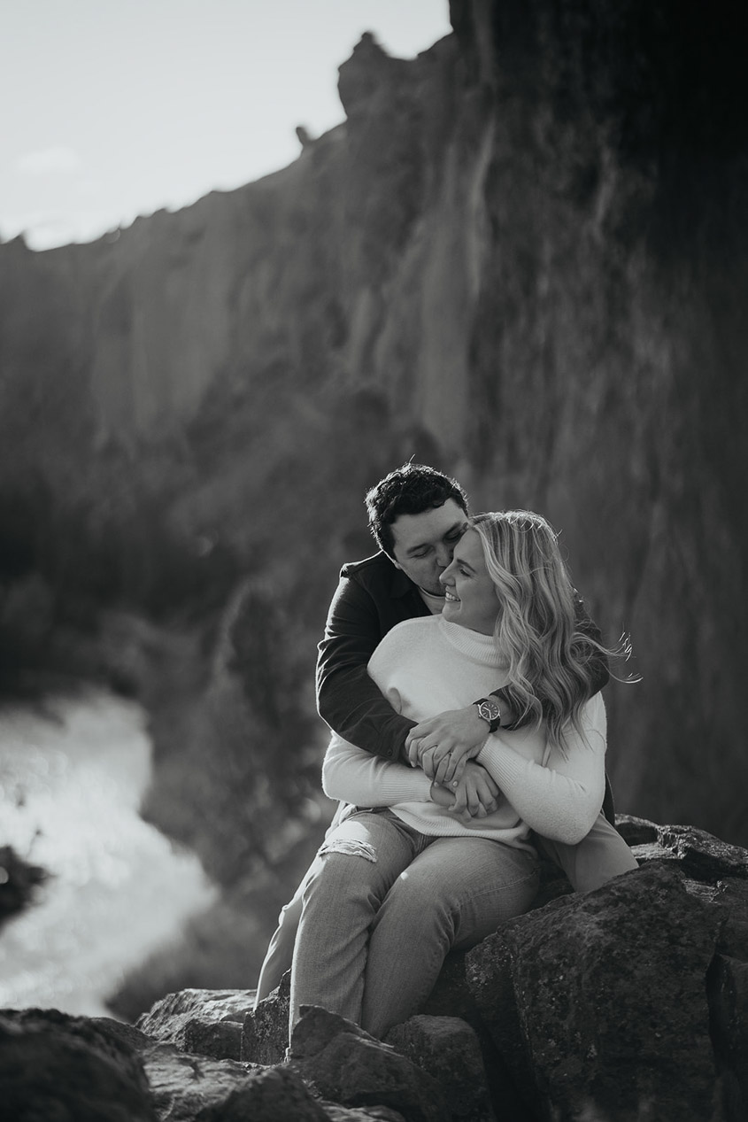 The engaged couple holding each other with smith rock in the background during their engagement session. 