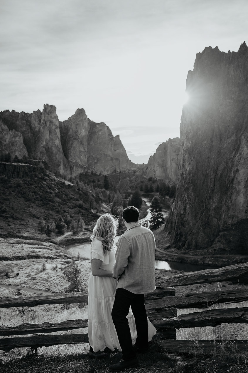 The couple holding hands with an iconic view of Smith Rock State Park in the background. 