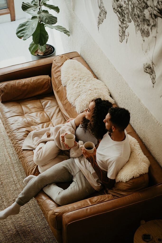 the bride and groom cuddling on a couch. 