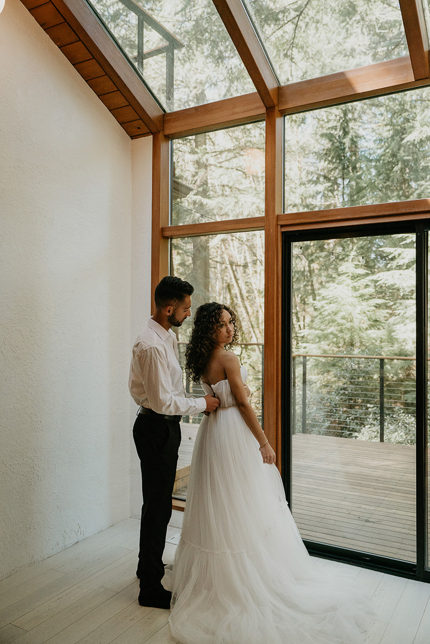 The groom helping the bride into her dress at the Woodlands house venue. .