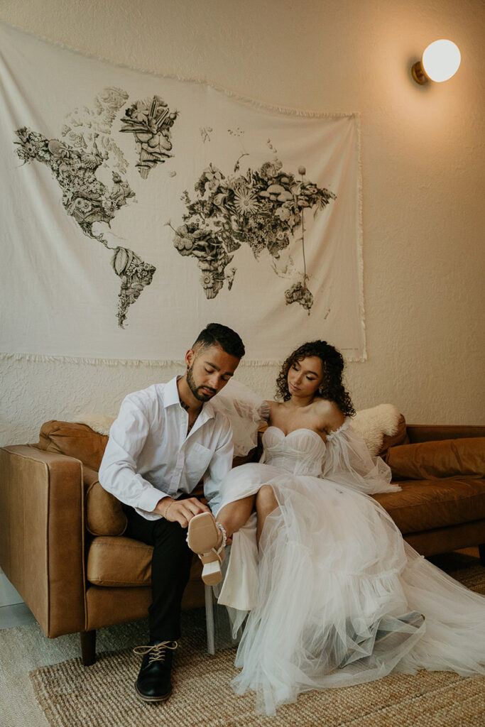 The groom helping his bride put on her heals. 