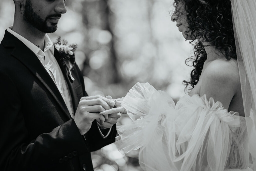 the groom putting a ring on the bride's finger. 