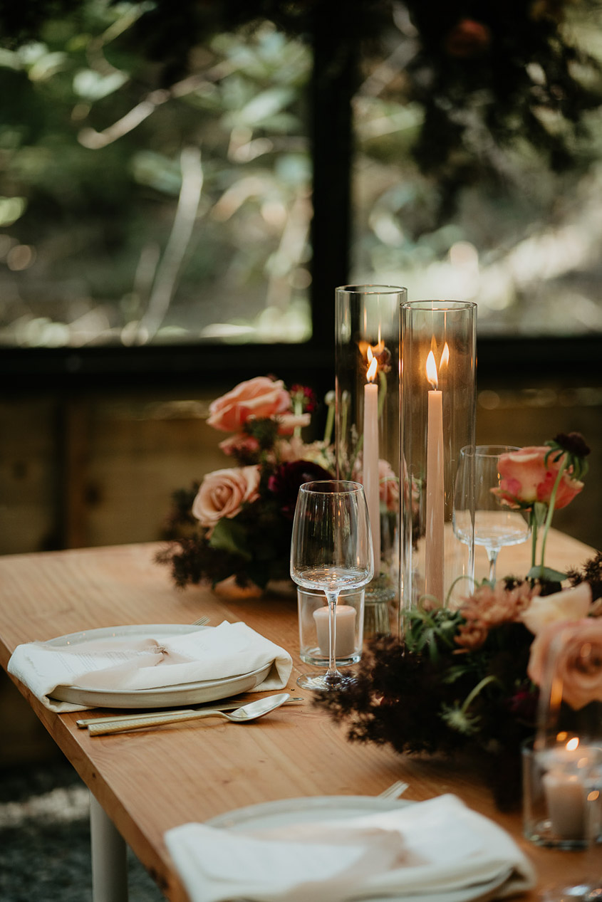 dinner plates, utensils, wine glasses, and table decorations at a green house at The Woodlands house venue. 