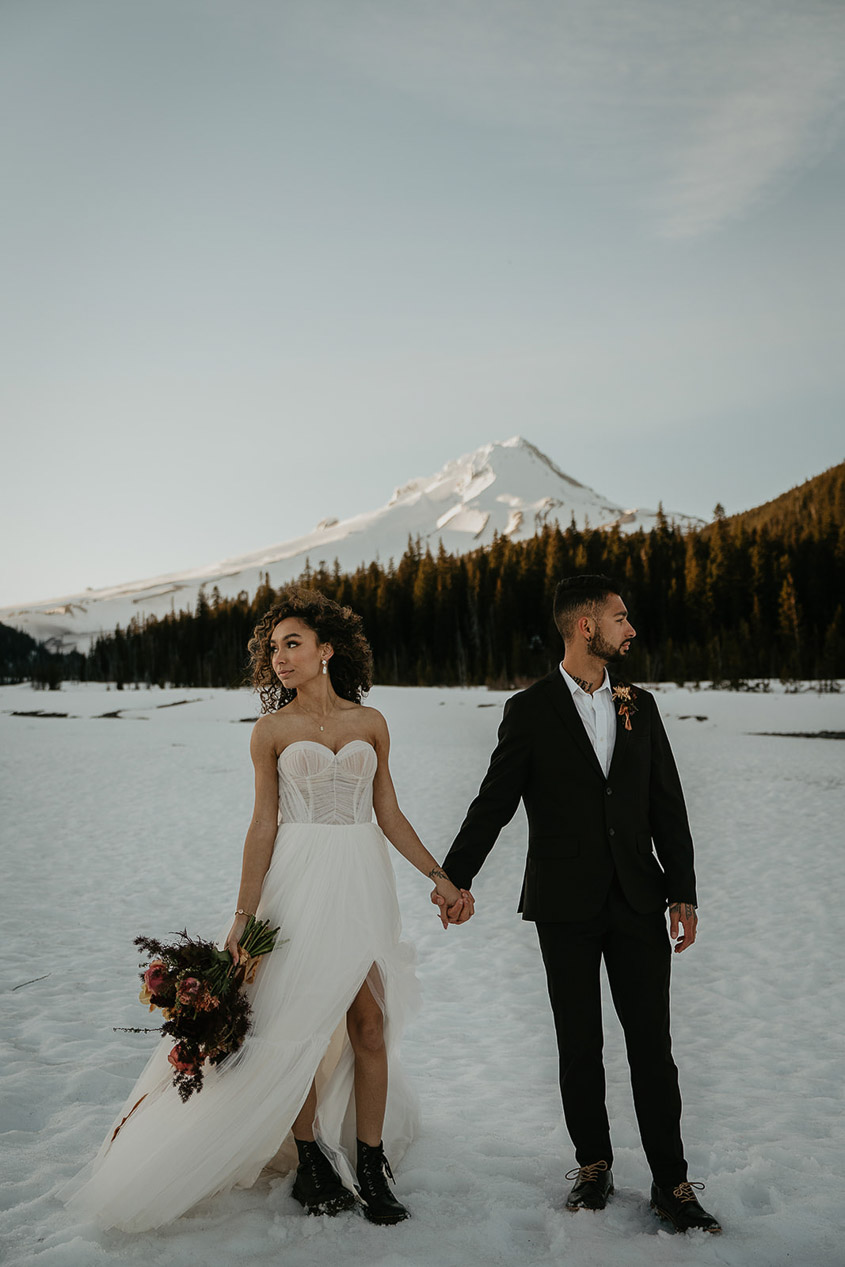 the newlyweds holding each other in the snow with Mt Hood in the background.